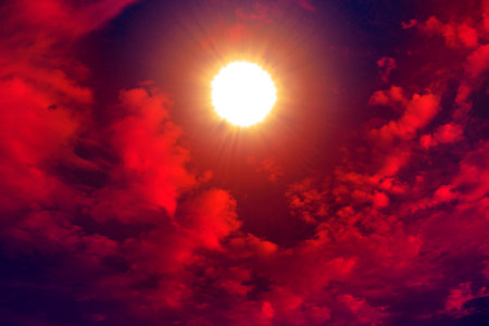 Abstract red background with sunlight and big clouds.の写真素材