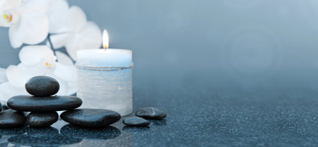 Spa stones with white orchid flowers.Black stones on a gray background, space for a text .の写真素材