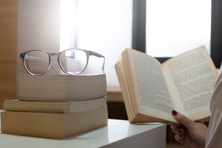 serious young student reading a book in a library selected focus on eyeglasses.の写真素材