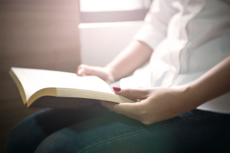 young woman reading a book near the windowの写真素材
