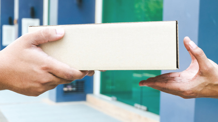 From hands to hands. Close-up of hands holding cardboard box at home
