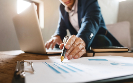 business man pointing at business document with laptop at a workplaceの写真素材