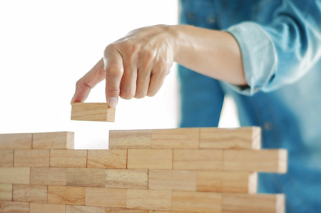 Woman in jeans shirt holding blocks wood game Building conceptの写真素材