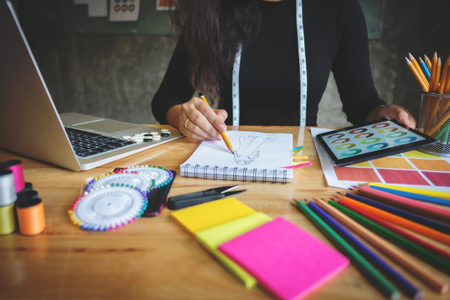 Close-up of young creative fashion designer working hard on project at a modern home officeの写真素材