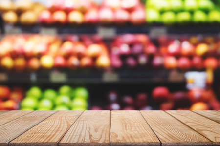 empty wooden table top with blurred with bokeh light of shopping mal fruit shelf background, used for display or montage your productの写真素材