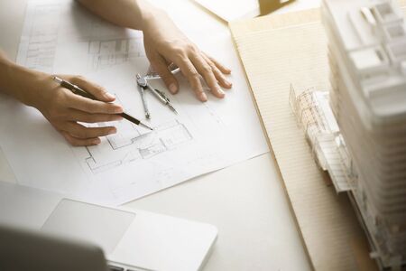 close up interior Architect working on blueprint with engineering tools