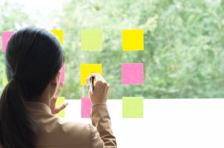 business colleague using notes on glass wall