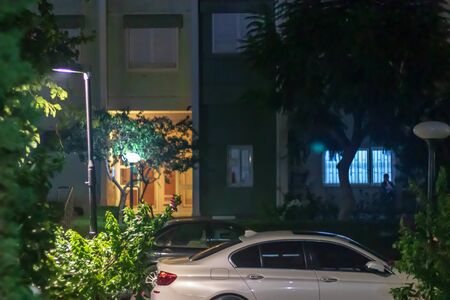 a night shoot of front of a building - there is a white car and some trees. photo has taken at izmir/turkey.の写真素材