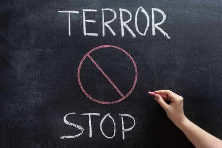 Hand with chalk on the background of STOP TERRORISM and prohibition signの写真素材