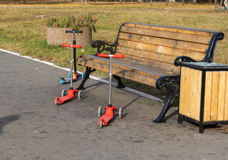 Three children's scooters at the bench in the autumn Parkの写真素材