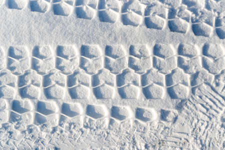 Footprints in the snow from car wheelsの写真素材