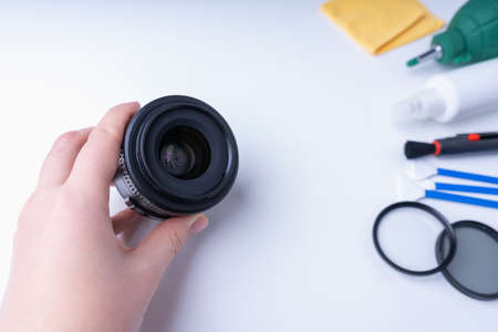 Photographer's hand holding a camera lens, accessories for cleaning the camera on a white backgroundの写真素材