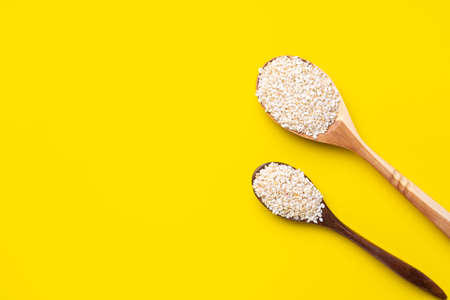 Two spoons with white sesame seeds on a yellow background. Top view.の写真素材