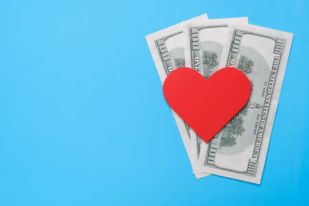 Red heart lies on American dollars on a blue background. Copy spaceの写真素材