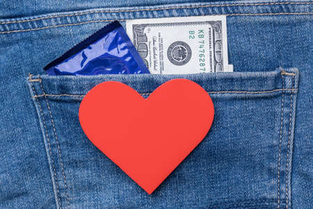 Love concept for money. One hundred dollars, condom and heart symbol on the back pocket of jeansの写真素材