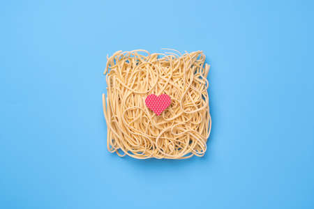 Instant noodles on blue background with red heart, fast food love concept. Ramenの写真素材