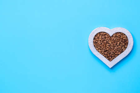 Buckwheat in the shape of a heart on a blue background. Silver heart. Copy-spaceの写真素材
