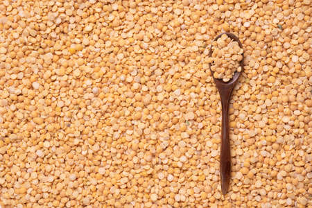A dark wooden spoon lies on dry yellow peas. Top viewの写真素材