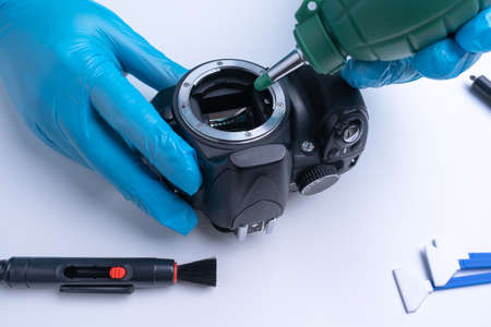 The technician cleans the matrix of the DSLR camera with a blower. Camera cleaning tool. Selective focusの写真素材