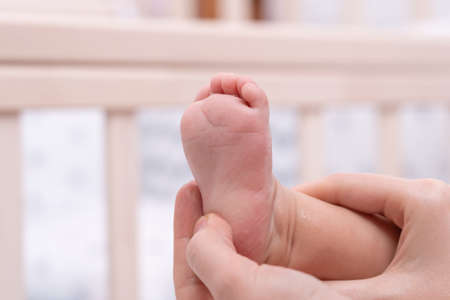 Mom gives a foot massage to the newborn while bathing in the bathroomの写真素材