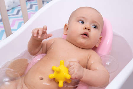 Infant bathes in the bathroom with her favorite toyの写真素材