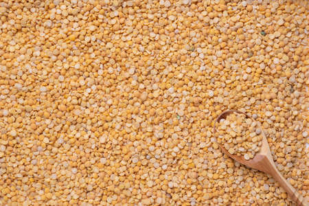 A wooden spoon lies on dry yellow peas.の写真素材