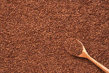 A full wooden spoon lies on buckwheat, top viewの写真素材