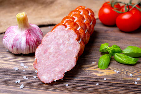 Homemade sausage cervelat with vegetables on a wooden background. National traditional cuisineの写真素材