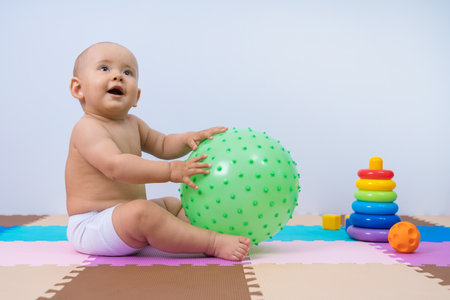 Toddler playing with a large rubber massage ballの写真素材