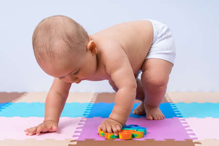 A newborn baby 7-12 months picks up a modern  toy from the floorの写真素材