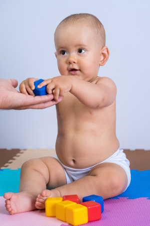 The toddler takes a blue plastic cube from his father's hands.の写真素材