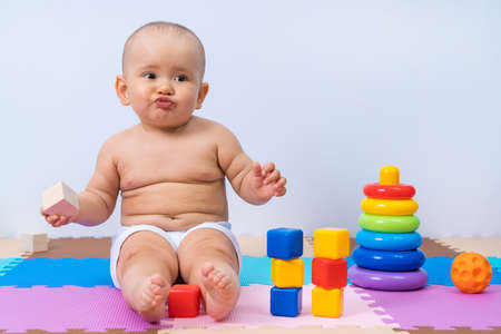 Offended child 8-12 months old, with toys in the playroom.の写真素材