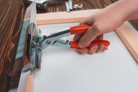 Hand with a tool for stretching the canvas. The business of producing paintings on canvas from photographs. Selective focusの写真素材