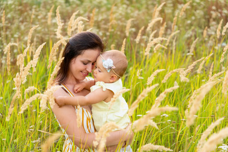 Portrait of a happy mother with her newborn daughter in her arms. Family photo in a wild field in the countrysideの写真素材