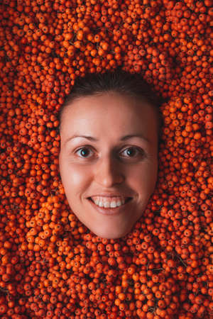 Portrait of a smiling woman among many orange rowan berriesの写真素材