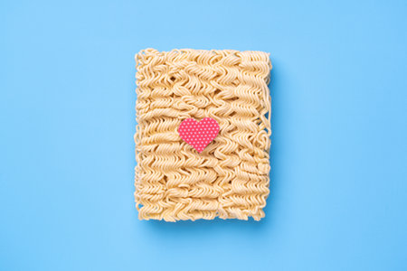 Instant noodles on blue background with red heart, fast food love conceptの写真素材