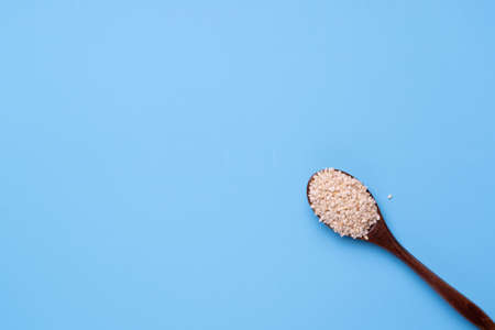 Wooden spoon with sesame seeds on a blue background.の写真素材