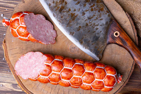 Homemade sausage on a cutting board and a large butcher's knife. wooden background with vegetablesの写真素材