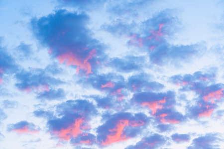 Beautiful cumulus cirrus clouds of purple pink color illuminated by the rays of the setting sunの写真素材