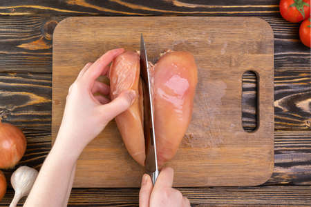 The chef's hands cut the chicken fillet with a knife. Chicken cutting technologyの写真素材