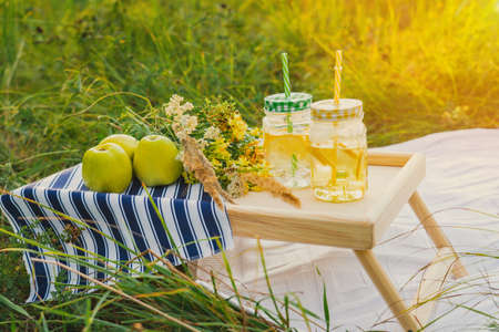 Summer picnic at sunset. Cans of ice and lemonade inside are on a small tableの写真素材