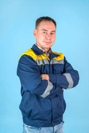 a man in a work jacket and jeans on a blue background