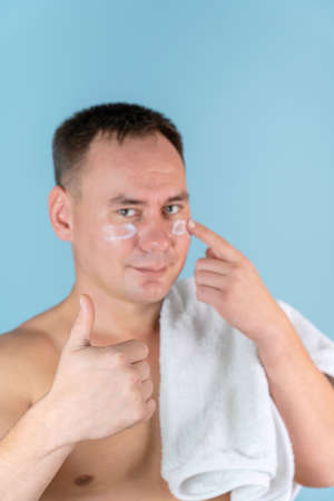 A man applies a face cream and gives a thumbs up, selective focusの写真素材