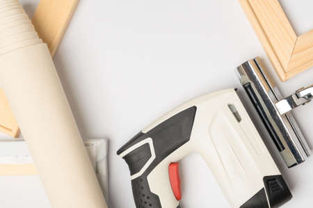 A tool for stretching natural canvas on a wooden stretcher. Gun stapler, forceps and wooden frame with canvas top viewの写真素材