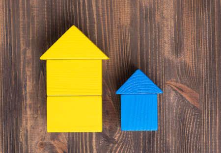 Large yellow and small blue house made of wooden cubes on a brown wooden background, top viewの写真素材