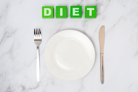 The concept of a diet. An empty white plate with a fork and a table knifeの写真素材