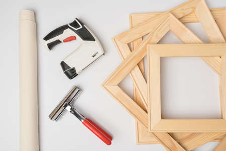 Print a photo on canvas. Canvas stretching equipment. A roll of canvas, tongs, wooden stretchers and a stapler pistol on a white backgroundの写真素材