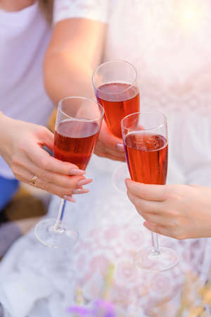 Three girls clink glasses of sparkling wine at a picnicの写真素材