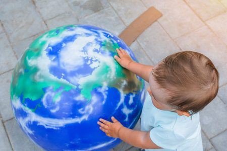 A child hugs a mock-up of planet earth in a platnetariumの写真素材