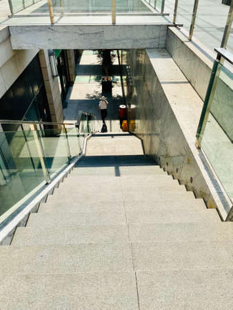 A vertical shot of a woman walking up the stairs in a modern buildingの写真素材